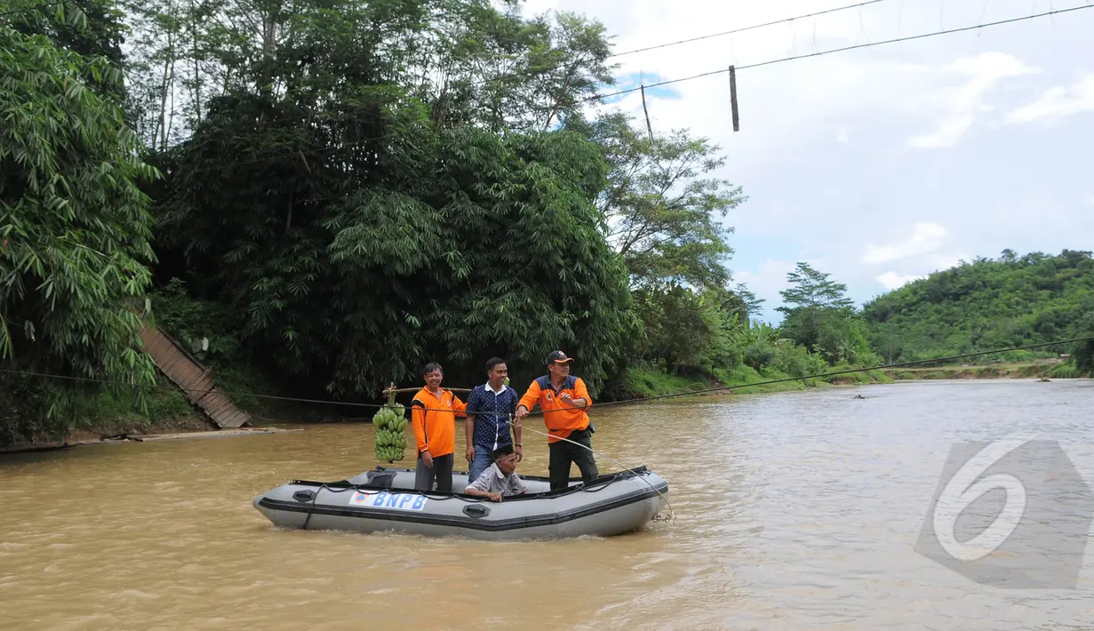Petugas dari BNPB membantu warga menyeberangi sungai Ciberang dengan perahu karet di Lebak, Banten, Senin (16/3). Pasca robohnya jembatan gantung di atas Sungai Ciberang, warga terpaksa menyeberang mengunakan perahu karet. (Liputan6.com/Herman Zakharia)