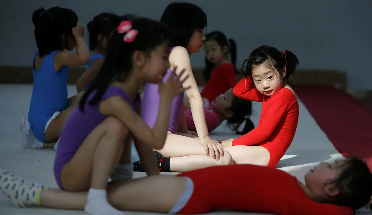 Sejumlah murid saling membantu saat berlatih senam lantai di sekolah atletik Shanghai Yangpu Youth Amateur, China (18/5). Latihan keras ini bisa membuat anak-anak menangis dan cedera ini diharapkan mampu menjadikan atlet berkualitas. (REUTERS/Aly Song)