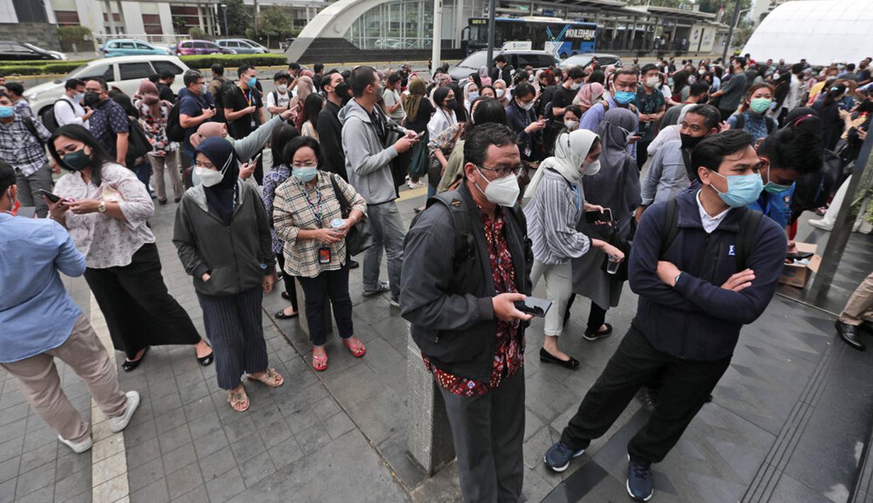 Warga menunggu di luar gedung perkantoran setelah gempa mengguncang Jakarta, Jumat (14/1/2022). Gempa magnitudo 6,7 yang berpusat di Banten pada pukul 16.05 WIB membuat kepanikan di berbagai daerah. (AP Photo)