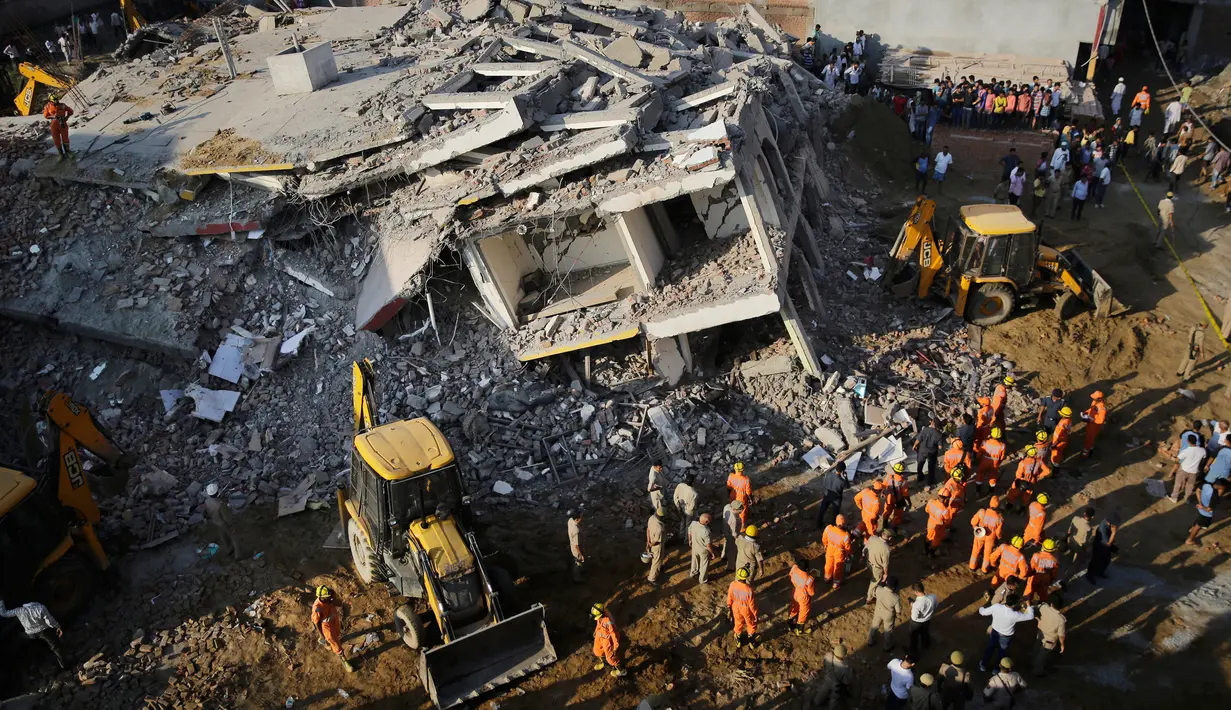 Tim penyelamat berada di lokasi gedung enam lantai yang ambruk di desa Shahberi, pinggiran kota New Delhi, India, Rabu (18/7). Gedung ambruk menimpa bangunan lain di sebelahnya yang dihuni warga. (AP Photo/Altaf Qadri)