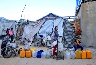 Rusak atau hancurnya sekitar 90 persen infrastruktur air dan sanitasi di Gaza juga menjadi penanda situasi krisis kemanusiaan yang ekstrem. Tampak dalam foto, anak-anak menunggu untuk mengisi wadah dengan air di kamp pengungsi Palestina, Nuseirat, Jalur Gaza Tengah pada Kamis 7 Mei 2026. (Eyad Baba/AFP)