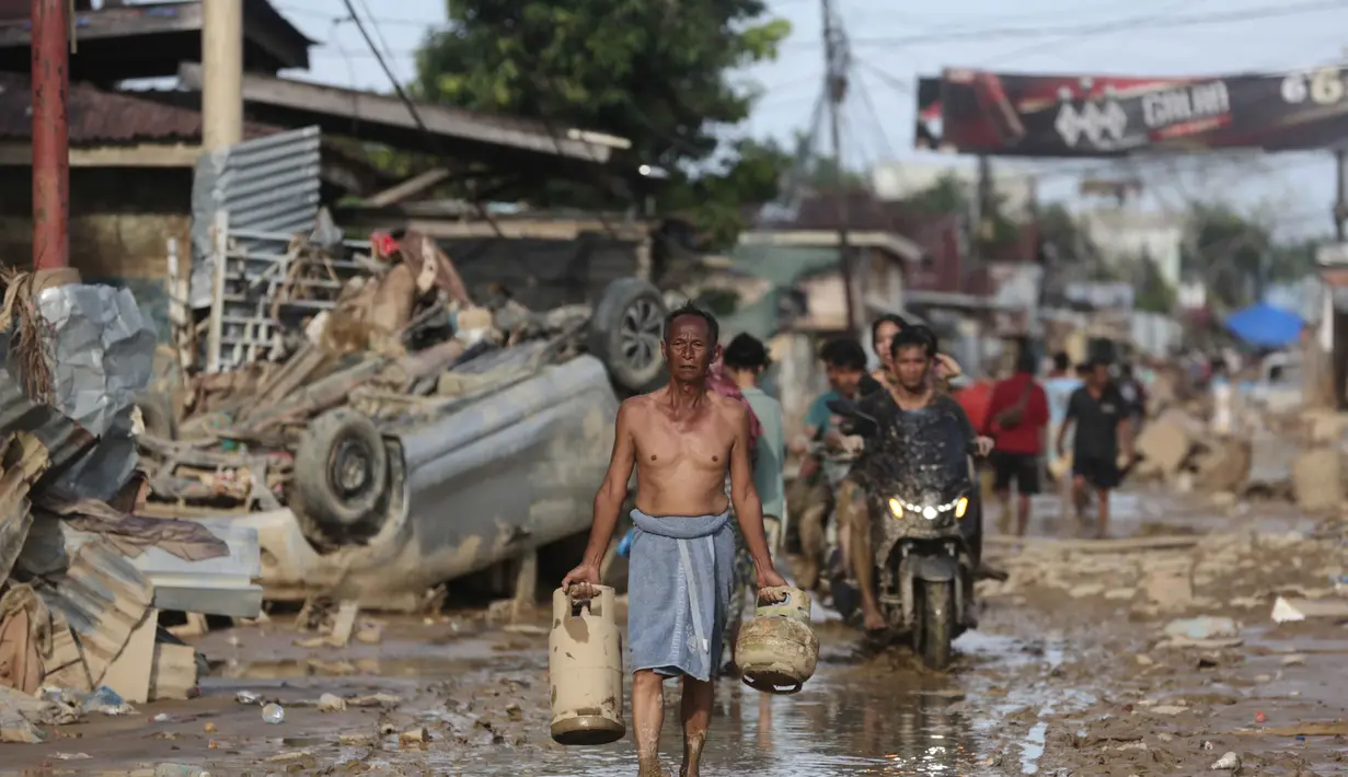 Banyak korban bencana banjir di Kabupaten Aceh Tamiang yang masih belum mendapatkan bantuan logistik berupa makanan. Tampak dalam foto, seorang korban selamat membawa tabung gas bekas di daerah terdampak banjir bandang di Aceh Tamiang, Sumatera, Kamis 4 Desember 2025. (AP Photo/Binsar Bakkara)