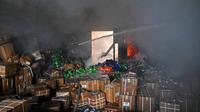Pemadam kebakaran berusaha memadamkan api di sebuah gudang di Kharkiv, Ukraina, yang hancur dalam serangan rudal Rusia. (dok. SERGEY BOBOK / AFP)