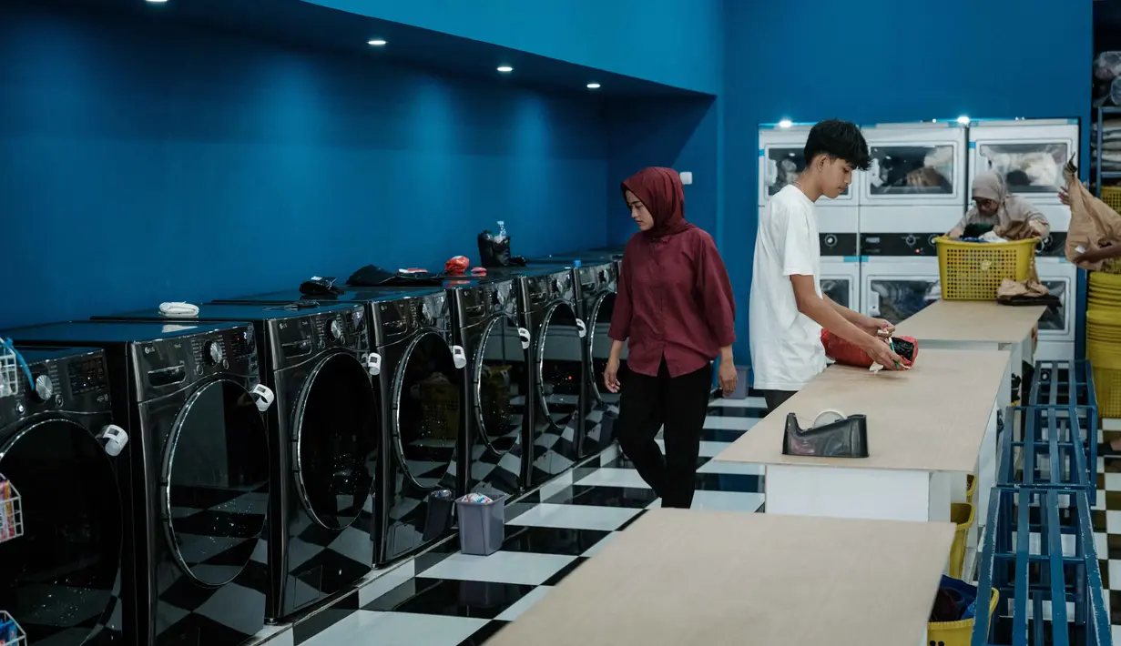 Diketahui, masih tersisa sekitar Rp 50 triliun plafon KUR yang siap disalurkan hingga akhir tahun untuk mendorong aktivitas Usaha Mikro, Kecil, dan Menengah (UMKM). Tampak dalam foto, warga menggunakan jasa layanan laundry pinggir jalan di Jakarta pada Sabtu 8 November 2025. (YASUYOSHI CHIBA/AFP)