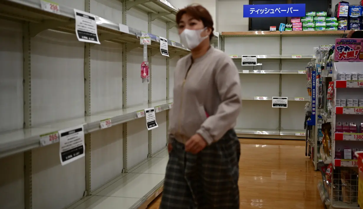 Seorang perempuan melewati rak-rak tisu toilet yang terjual habis di sebuah toko di Tokyo, Minggu (1/3/2020). Warga Jepang yang sedang waspada wabah virus corona tipe baru, Covid-19 dilanda kepanikan setelah muncul gosip bahwa China tidak akan lagi mengekspor kertas toilet. (CHARLY TRIBALLEAU/AFP)