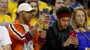 Pembalap Formula 1, Lewis Hamilton dan pemain Barcelona, Neymar Jr merekam pertandingan gim kedua Final NBA antara Cleveland Cavaliers melawan Golden State Warriors di Oracle Arena, Oakland, California, AS, (4/6). (Ezra Shaw/Getty Images/AFP)