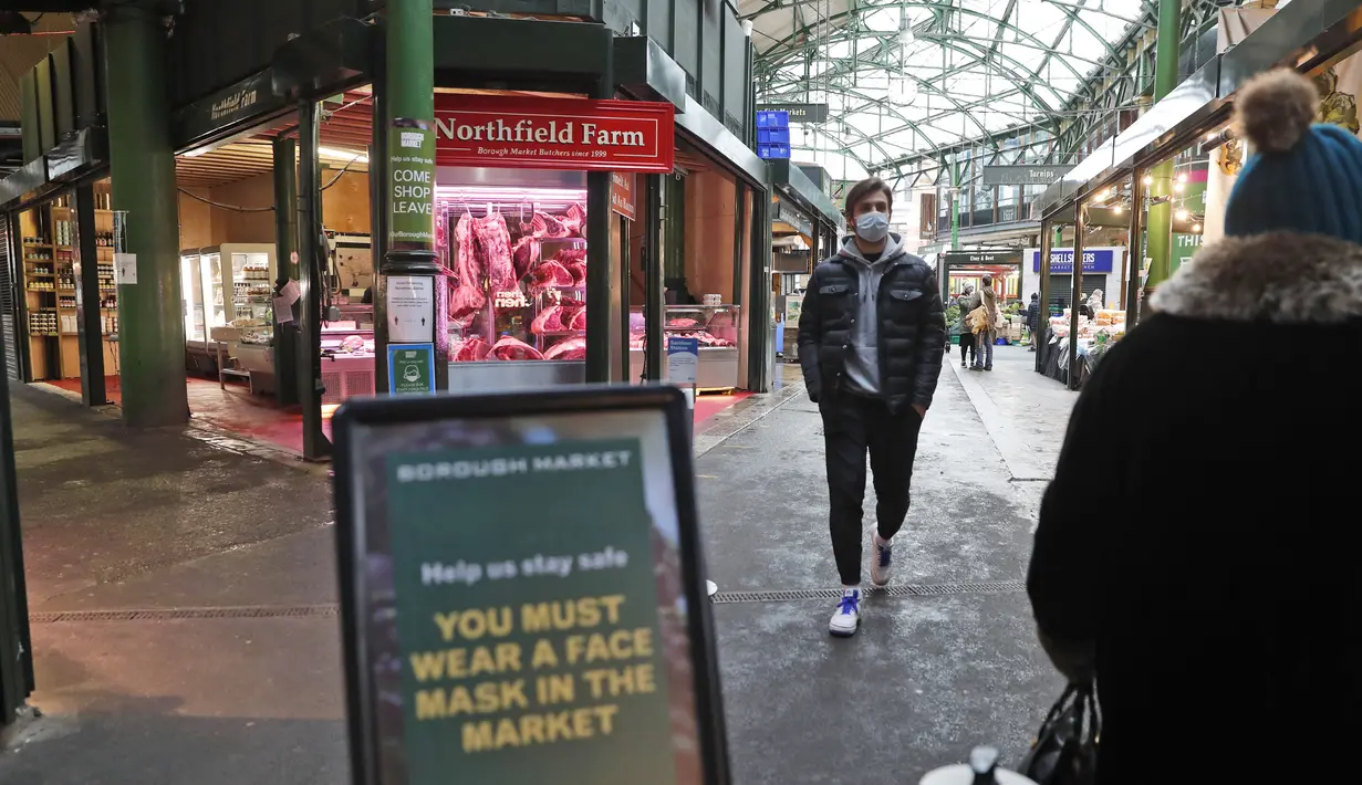 Orang-orang yang memakai masker berjalan di sepanjang Borough Market di London selatan selama penguncian nasional (lockdown) ketiga Inggris, Selasa (12/1/2021). Borough Market menjadi tempat pertama yang mewajibkan pemakaian masker di luar ruangan. (AP Photo/Alastair Grant)
