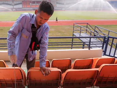 Seorang pekerja mengecat bangku tribun Stadion Si Jalak Harupat (SJH), Bandung, Sabtu (21/10/2023). Persiapan veneu untuk Piala Dunia U-17 2023 itu sudah hampir 100 persen. (Bola.com/Bagaskara Lazuardi)