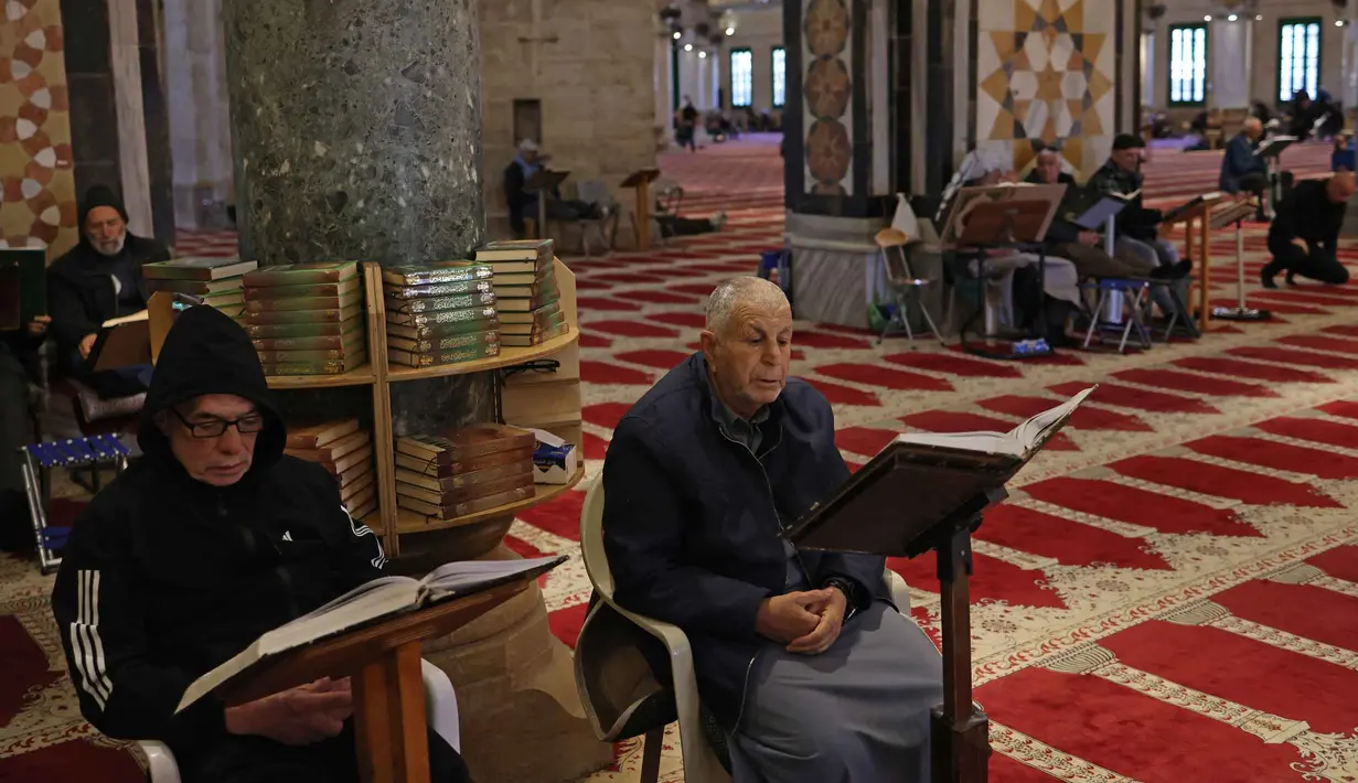 Bangunan berkubah emas ini melindungi Batu Shakhrah, yang diyakini sebagai titik awal perjalanan Nabi Muhammad SAW menuju Sidratul Muntaha dalam peristiwa Isra Miraj. Tampak dalam foto, para pria Palestina membaca Al-Quran di dalam Kubah Batu di kompleks Masjid al-Aqsa, Yerusalem menjelang waktu berbuka puasa selama bulan suci Ramadan 1447 Hijriah pada Rabu 25 Februari 2026. (AHMAD GHARABLI/AFP)
