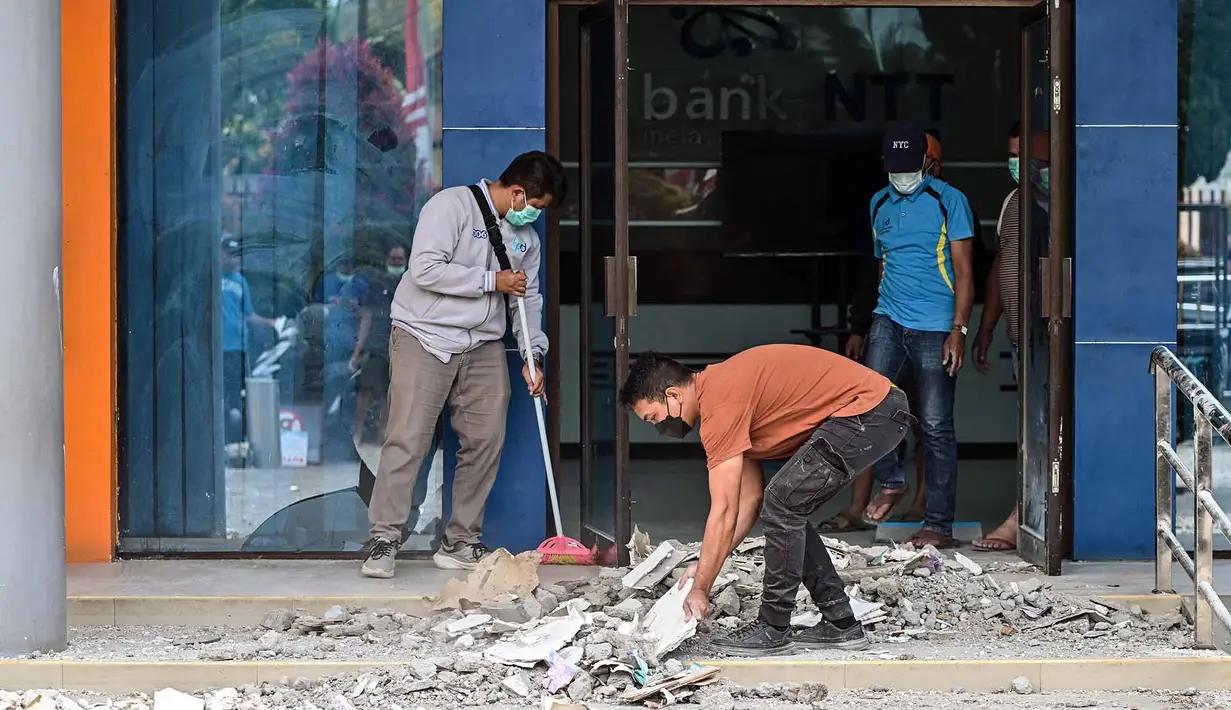 Para pekerja membersihkan puing-puing dari sebuah gedung bank yang rusak akibat gempa berkekuatan magnitudo 7,7 di Ruteng, Manggarai, Nusa Tenggara Timur, Minggu, 16 Agustus 2026. (AFP/ Juni Kriswanto)