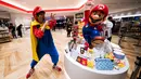 Seorang pria mengenakan kostum salah satu tokoh ikonik dari Nintendo, Mario berpose di sebelah merchandise yang berkaitan dengan permainan ini selama pratinjau pers di toko baru Nintendo di Tokyo, 19 November 2019. Nintendo akan meresmikan toko pertamanya di Tokyo pada pekan ini. (Behrouz MEHRI/AFP)