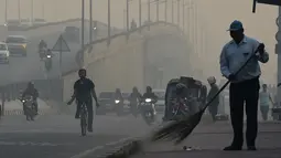 Petugas membersihkan jalan di tengah kondisi kabut asap tebal di New Delhi (30/10). Tingkat kabut melonjak selama musim dingin di Delhi, ketika kualitas udara sering melampaui tingkat aman Organisasi Kesehatan Dunia. (AFP Photo/Prakash Singh)