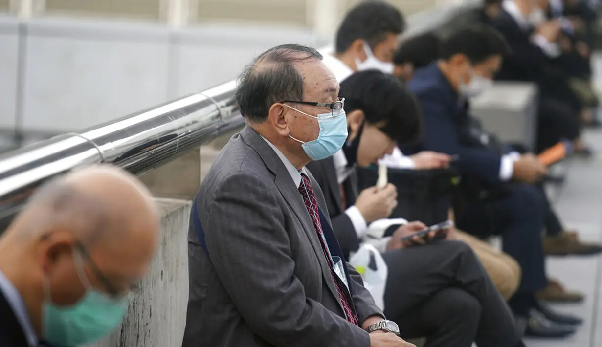 Orang-orang yang memakai masker untuk membantu mengekang penyebaran virus corona COVID-19 beristirahat di Chiba, Tokyo, Rabu, 28 Oktober 2020. Tokyo mengonfirmasi lebih dari 170 kasus virus corona COVID-19 baru pada 28 Oktober 2020. (AP Photo/Eugene Hoshiko)