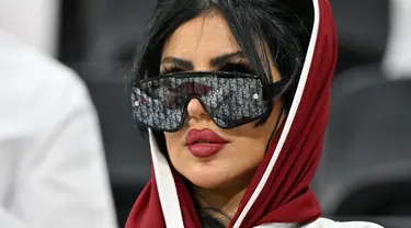 Seorang wanita pendukung Qatar mengenakan kaca mata hitam menghadiri pertandingan Grup A Piala Dunia Qatar 2022 antara Qatar dan Ekuador di Stadion Al-Bayt di Al Khor, utara Doha pada 20 November 2022. (AFP/Glyn Kirk)