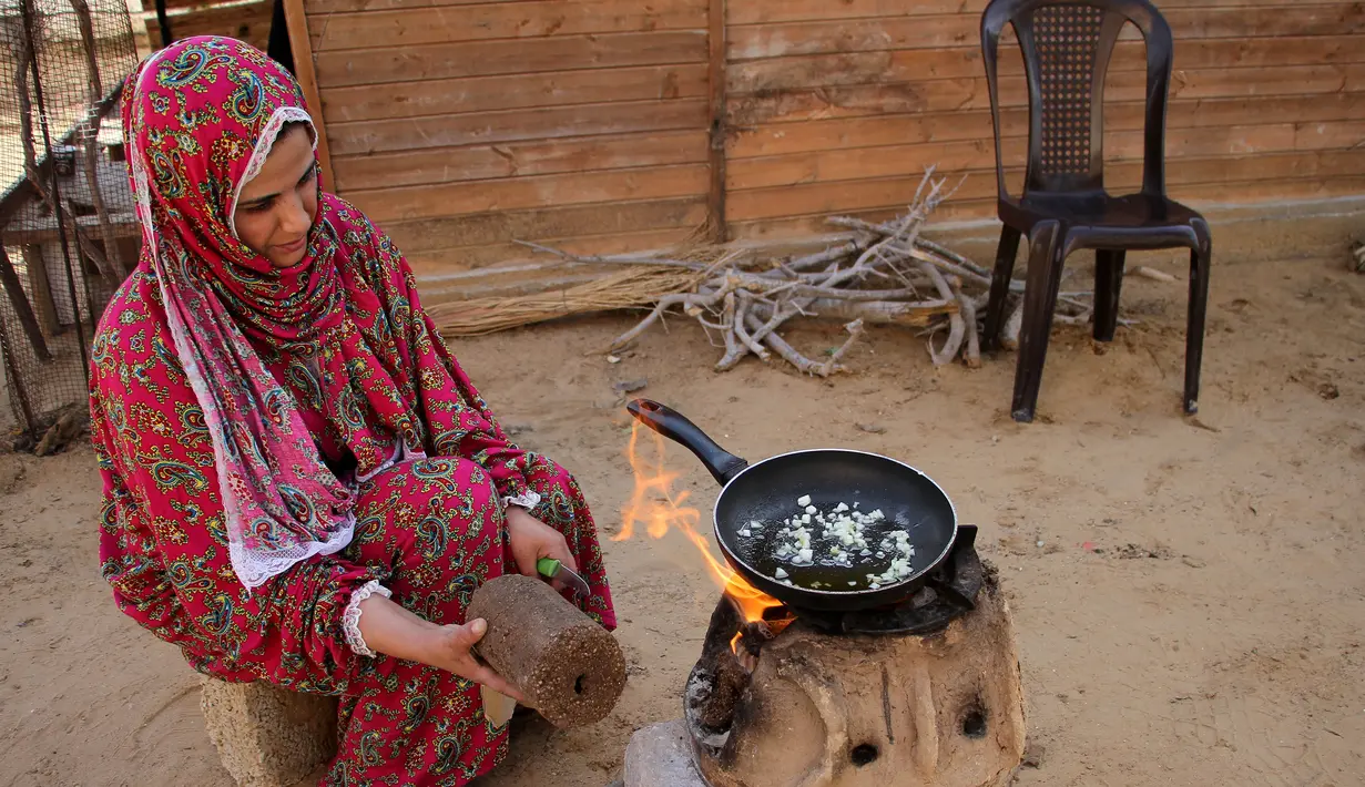 Seorang wanita menggunakan kayu pomace (ampas) sebagai bahan bakar untuk memasak di rumahnya di Kota Khan Younis, Jalur Gaza, Palestina, 7 November 2020. Pekerja Palestina mengubah limbah produksi minyak zaitun menjadi kayu pomace yang dapat digunakan sebagai bahan bakar. (Xinhua/Rizek Abdeljawad)