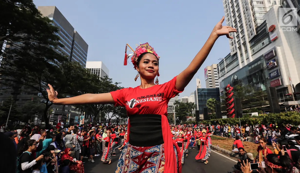 Seorang penari diikuti ribuan peserta membawakan Tari Kembang Jatoh dari Betawi saat CFD di Senayan, Jakarta, Minggu (12/8). Kegiatan ini digelar menyambut HUT Ke-73 RI dan Asian Games 2018. (Liputan6.com/Fery Pradolo)