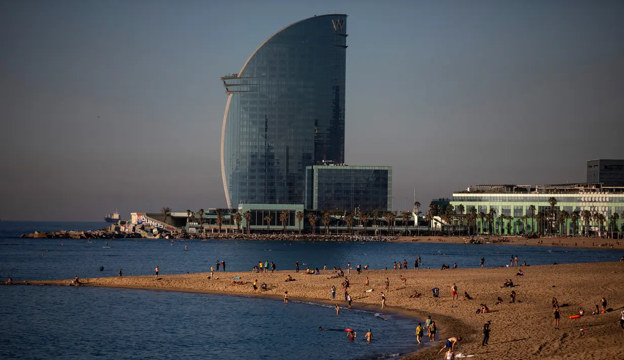 Orang-orang menikmati pantai di Barcelona, Spanyol, Rabu, (20/5/2020). Barcelona mengizinkan orang untuk berjalan di pantai Rabu, untuk pertama kalinya sejak dimulainya penutupan virus lebih dari dua bulan lalu. Berjemur dan berenang rekreasi masih tidak diizinkan. (AP Photo/Emilio Morenatti)