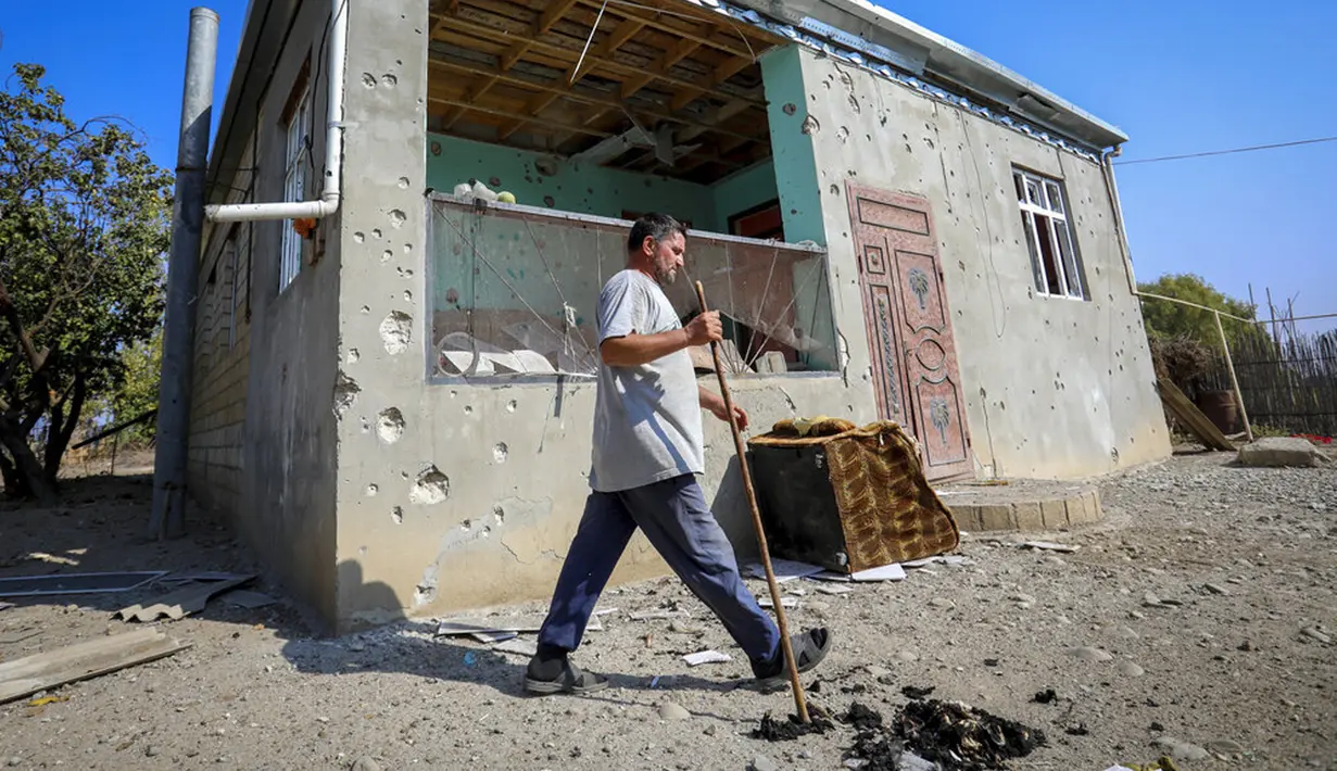 Seorang pria berjalan melewati sebuah rumah yang rusak akibat penembakan selama pertempuran Azerbaijan dan Armenia dalam memperebutkan wilayah Nagorno-Karabakh di Agdam, Azerbaijan, Senin (19/10/2020). Pertempuran di Nagorno-Karabakh berkecamuk selama lebih dari tiga minggu. (AP Photo/Aziz Karimov)