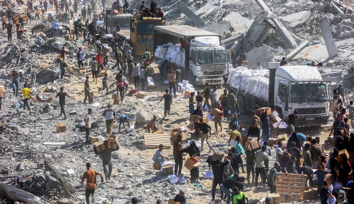 Pasca pemberlakukan kesepakatan gencatan senjata antara Israel dan Hamas pada Jumat 10 Oktober 2025, warga memadati kawasan Khan Younis untuk mengumpulkan bantuan yang masuk melalui pos perbatasan Karem Abu Salem, bagian selatan Jalur Gaza, pada Minggu 12 Oktober 2025. (Omar AL-QATTAA/AFP)