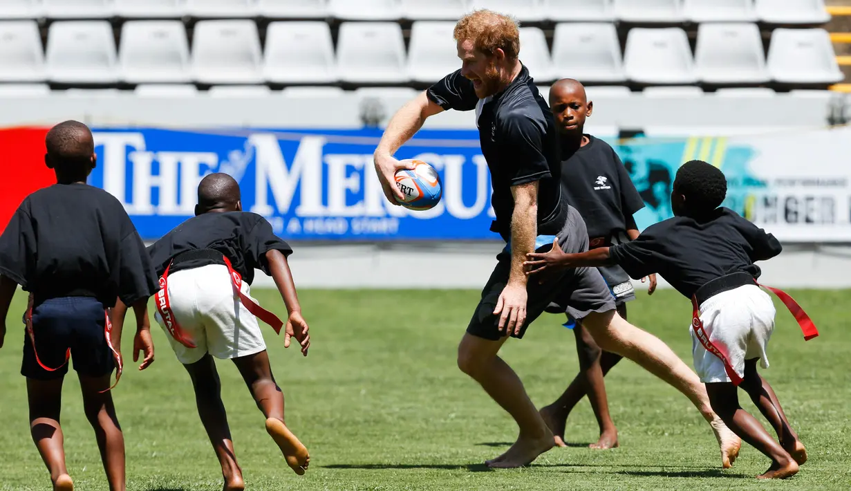 Pangeran Harry  bermain rugby dengan anak - anak di Durban , Afrika Selatan, Selasa (1/12). Pangeran Harry di Afrika Selatan untuk mengadakan acara amal yang didirikannya bersama Pangeran Lerotholi Seeiso. (REUTERS/Rogan Ward) 