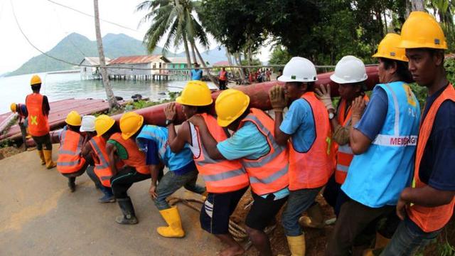 Karyawan PT PLN (Persero) bergotong-rotong mengangkat tiang yang akan digunakan untuk penyangga kabel listrik di Natuna, Kepulauan Riau. (Foto: Humas PLN)