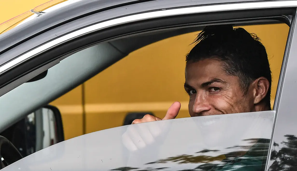 Pemain Juventus Cristiano Ronaldo memberi isyarat dari dalam mobil setelah menghadiri latihan di Continassa, Turin, Italia, Selasa (19/5/2020). Pemain Juventus kembali berlatih di tengah pandemi virus corona COVID-19. (Marco Bertorello/AFP)