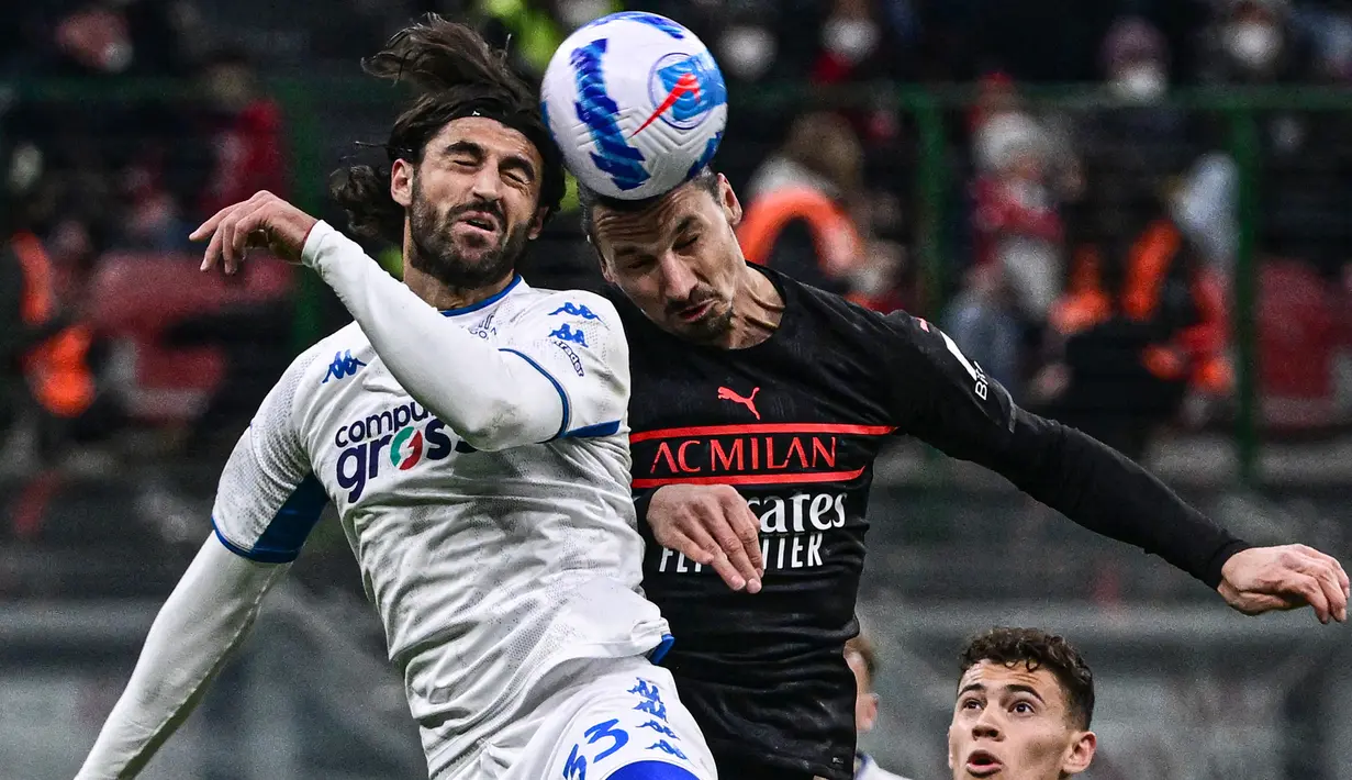 Bek Empoli Sebastiano Luperto (kiri) dan penyerang AC Milan Zlatan Ibrahimovic melakukan sundulan saat berebut bola pada pekan ke-29 Liga Italia di Stadion San Siro, Minggu (13/3/2022) dini hari WIB.  AC Milan menang tipis 1-0 atas tamunya, Empoli. (Miguel MEDINA / AFP)
