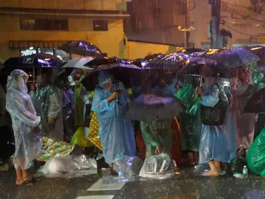Sejumlah orang memakai jas hujan dan memegang payung demi menghadiri upacara kremasi Raja Thailand Bhumibol Adulyadej di Bangkok, Selasa (24/10). Upacara pemakaman sendiri akan berlangsung selama lima hari mulai Kamis, 26 Oktober 2017. (AP/Sakchai Lalit)