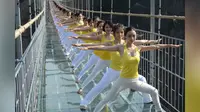 Tanpa mengenal takut, 100 yogi melakukan latihan di jembatan gantung transparan.