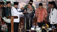 Sekjen Pagar Nusa M Nabil Haroen memberikan jubah kehormatan pencak silat Nahdlatul Ulama (PSNU) Pagar Nusa kepada Kapolri Jendral Tito Karnavian pada acara pembukaan Kongres III PSNU di TMII, Jakarta, Rabu (3/5). (Liputan6.com/Johan Tallo)