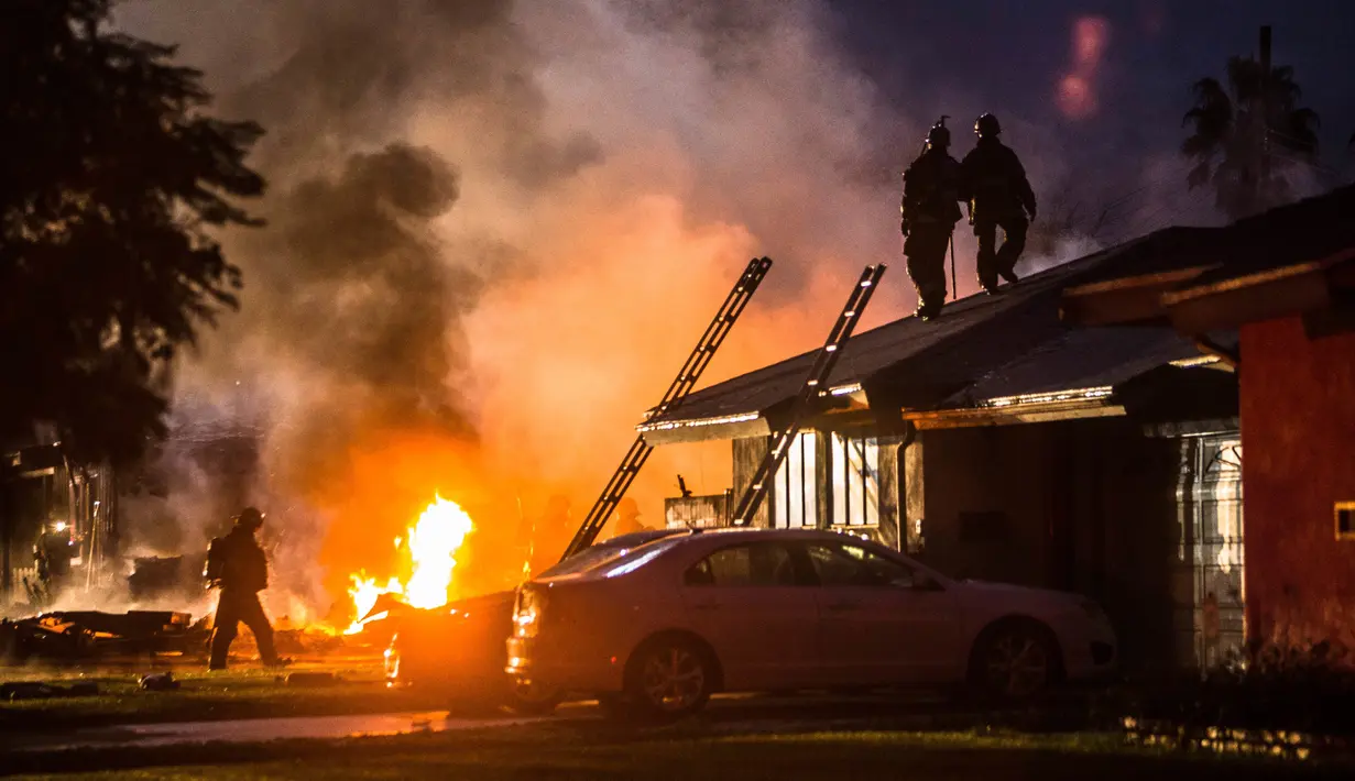 Kobaran api terlihat setelah sebuah pesawat jatuh menimpa dua rumah di Riverside, California, Senin (27/2). Empat orang dilaporkan tewas dan dua lainnya terluka akibat insiden yang memicu kebakaran hebat itu. (Watchara Phomicinda/The Press-Enterprise/AP)