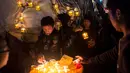 Peserta menyalakan lentera kecil untuk dilekatkan bersama balon udara selama Festival Tazaungdaing di Taunggyi, Myanmar pada 14 November 2018. Festival tahunan itu diselenggarakan guna merayakan berakhirnya musim hujan. (Ye Aung THU / AFP)