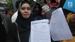 Nasabah Pandawa Group menunjukkan dokumen perjanjian saat mendatangi PN Jakarta Pusat, Rabu (24/5). Kedatangan para kreditur yang terjebak investasi bodong itu untuk melakukan verifikasi jumlah tagihan agar dana mereka kembali. (Liputan6.com/Helmi Afandi)