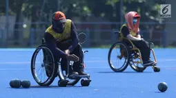 Atlet Para Games Indonesia cabang olahraga Lawn Bowls melakukan lemparan saat latihan di Lapangan Hoki Kompleks GBK, Jakarta, Selasa (18/9). Latihan ini adaptasi lapangan sekaligus persiapan jelang Asian Para Games 2018. (Liputan6.com/Helmi Fithriansyah)