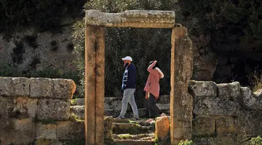 Pasangan mengunjungi situs kota Yunani kuno Kirene di pinggiran kota Libya Shehhat, di sebelah timur kota pesisir Benghazi (13/12/2019). Kirene merupakan kota tertua dan terpenting di antara lima kota Yunani yang didirikan sebagai simbol koloni bangsa Yunani di Thera sekitar 630 SM. (AFP/Abdullah Do