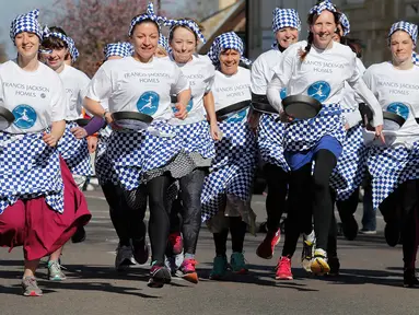 Para peserta melakukan pemanasan sebelum lomba lari dengan membawa pancake dalam lomba tahunan Pancake Trans-Atlantic, di kota Olney, Buckinghamshire, Inggris, Selasa (5/3). Peserta harus membolak-balikan pancake sambil tetap berlari. (AP/Frank Augstein)