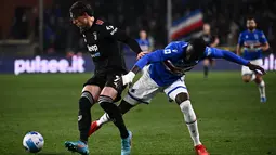 Penyerang Juventus Dusan Vlahovic berebut bola dengan bek Sampdoria Omar Colley pada pekan ke-29 Liga Italia di Stadion Luigi Ferraris di Stadion Luigi Ferraris, Minggu (13/3/2022) dini hari WIB. Dua gol Alvaro Morata membantu Juventus menekuk Sampdoria dengan skor 3-1. (Marco BERTORELLO/AFP)