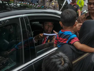 Presiden Joko Widodo membagikan buku kepada warga seusai acara makan siang bersama kepala negara serta delegasi negara-negara peserta Konferensi Asia Afrika di Jalan Cicendo, Bandung, Jumat (24/4/2015). (Liputan6.com/Faizal Fanani)