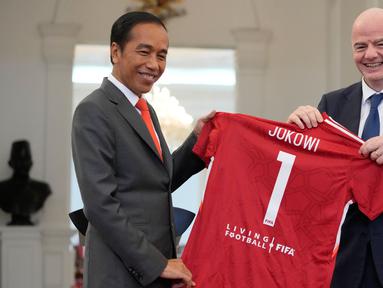 Presiden Joko Widodo (kiri) memberikan jarsey kepada Presiden Induk Asosiasi Sepakbola Dunia (FIFA) Gianni Infantino saat bertemu di Istana Negara, Jakarta, Selasa (18/10/2022). Pertemuan ini khusus antara FIFA dengan pemerintah Indonesia. (AP Photo/Achmad Ibrahim)