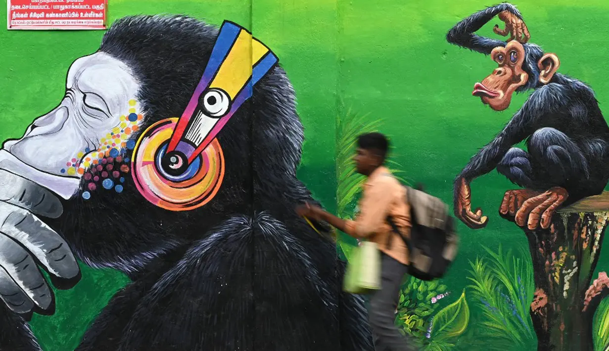 Seorang anak laki-laki berjalan melewati mural di sepanjang pinggir jalan di Chennai, India, 13 September 2021. India bersiap hadapi kemungkinan lonjakan kasus COVID-19 sekitar musim festival September hingga November. (ARUN SANKAR/AFP)