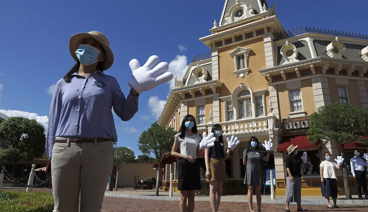 Pegawai yang mengenakan masker untuk mencegah penyebaran COVID-19 menyambut pengunjung di Disneyland Hong Kong, Kamis (18/6/2020). Disneyland Hong Kong kembali beroperasi pada 18 Juni 2020 dengan menerapkan sejumlah protokol kesehatan baru. (AP Photo/Kin Cheung)