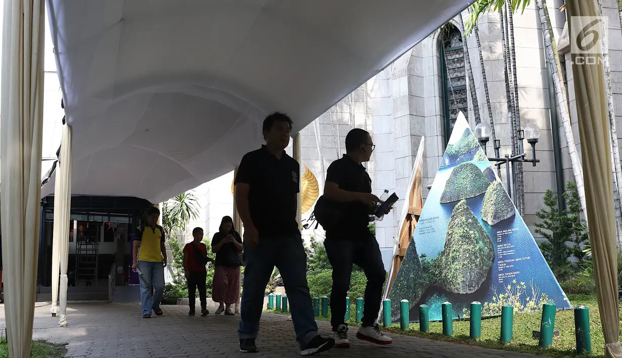 Jemaat melintas saat penyelesaian pembuatan tenda dan dekorasi Natal di Gereja Katedral, Jakarta, Kamis (20/12). Pendirian tenda dilakukan untuk melayani umat yang biasanya membeludak saat pelaksanaan Misa Natal. (Liputan6.com/Immanuel Antonius)