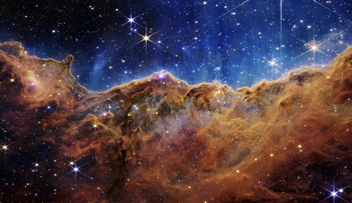 Gambar ini dirilis oleh NASA pada 12 Juli 2022, menunjukkan tepi daerah pembentuk bintang muda di dekatnya, NGC 3324 di Nebula Carina. Ditangkap dalam cahaya inframerah oleh Near-Infrared Camera (NIRCam) melalui Teleskop Luar Angkasa James Webb, gambar ini mengungkapkan area kelahiran bintang yang sebelumnya tak terlihat, menurut NASA. (NASA, ESA, CSA, and STScI via AP)