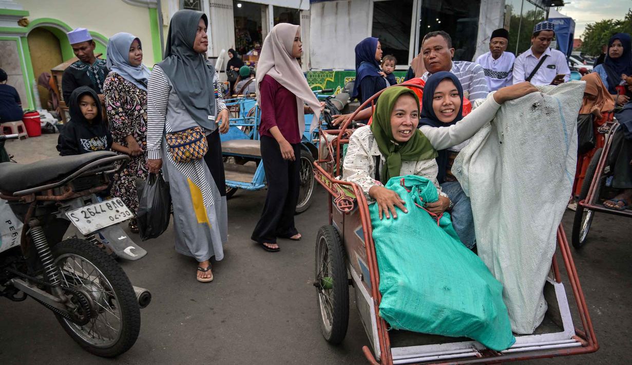 Pasar ini juga menjadi pusat perbelanjaan kebutuhan warga, termasuk baju takwa, peci, dan sajadah, selama Ramadan dan untuk menyambut Hari Raya Idul Fitri. Tampak dalam foto, para wanita Muslim menaiki becak setelah berbelanja selama bulan suci Ramadan di dekat Masjid Sunan Ampel, Surabaya, Jawa Timur, pada Minggu 8 Maret 2026. (JUNI KRISWANTO/AFP)