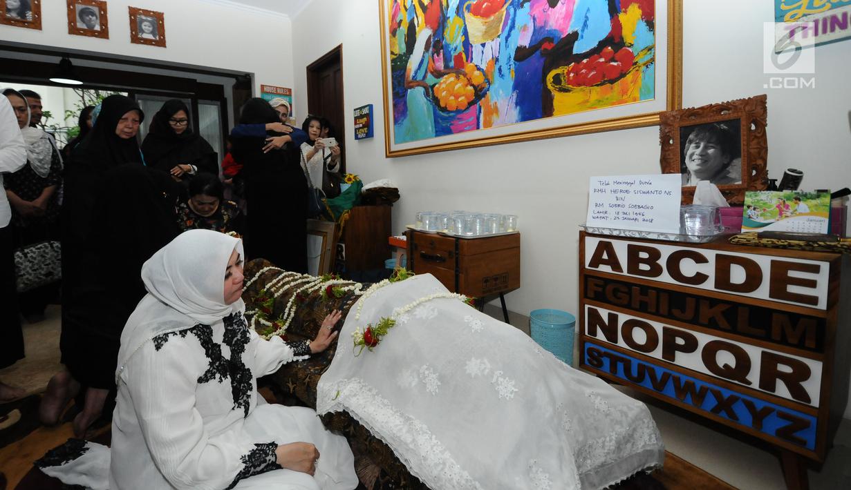 Istri alm RMH Heroe Siswanto NS atau dikenal Sys NS, Shanty Widhiyanti berdoa di sisi jenazah di rumah duka, Jakarta, Selasa (23/1). Sys NS wafat diusia 61 tahun akibat serangan jantung. (Liputan6.com/Helmi Fithriansyah)
