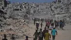 Pengungsi Palestina berjalan melewati bangunan-bangunan yang hancur saat mereka kembali ke rumah mereka di kawasan Zeitoun, Kota Gaza, pada Jumat 10 Oktober 2025, setelah Israel dan Hamas sepakat untuk menghentikan sementara perang mereka dan membebaskan sandera yang tersisa. (AP Photo/Jehad Alshrafi)