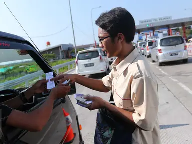 Petugas Lintas Marga Sedaya (LMS) menghampiri pengendara untuk menagih uang tol di pintu keluar Pejagan, Jawa Tengah, Sabtu (2/7). Sistem 'jemput bola' pembayaran tiket tol itu untuk mengurai kemacetan saat arus mudik. (Liputan6.com/Angga Yuniar)