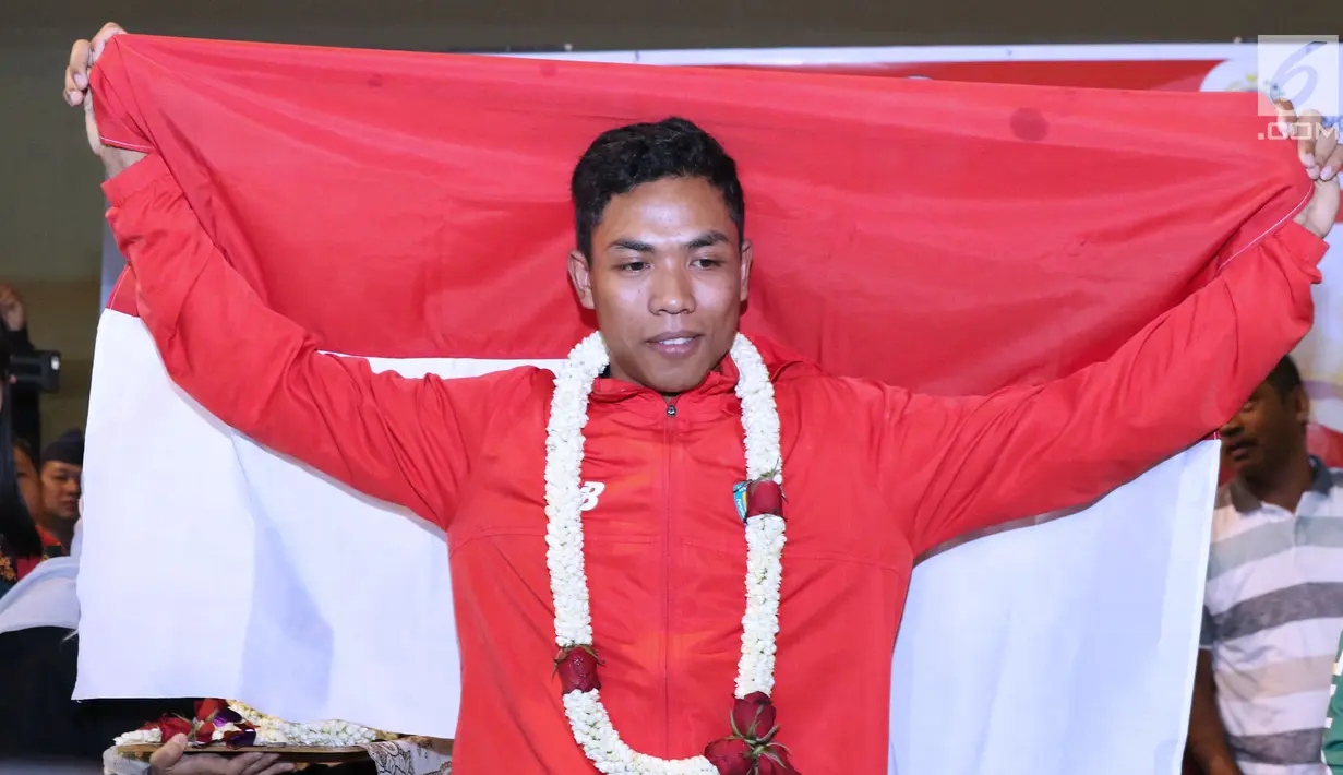 Pelari muda Indonesia, Lalu Muhammad Zohri membentangkan bendera Merah Putih saat penyambutan di Terminal 3 Bandara Soetta, Tangerang, Selasa (17/7). Lalu M Zohri meraih emas 100m putra di Kejuaraan Dunia Atletik U-20. (Liputan6.com/Helmi Fithriansyah)