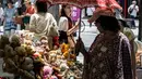 Seorang perempuan (kanan) menggunakan payung untuk berlindung dari teriknya sinar matahari saat melihat-lihat boneka beruang yang dijual di pasar barang antik di pusat kota Tokyo, Jepang, Senin (17/7/2023). (Richard A. Brooks / AFP)