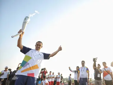 Gubernur DKI Jakarta Anies Baswedan mengangkat obor saat puncak Kirab Obor Asian Games 2018 di Jakarta, Sabtu (18/8). Obor diarak mulai dari Monumen Nasional (Monas) menuju Stadion Utama Gelora Bung Karno (GBK). (Liputan6.com/Faizal Fanani)